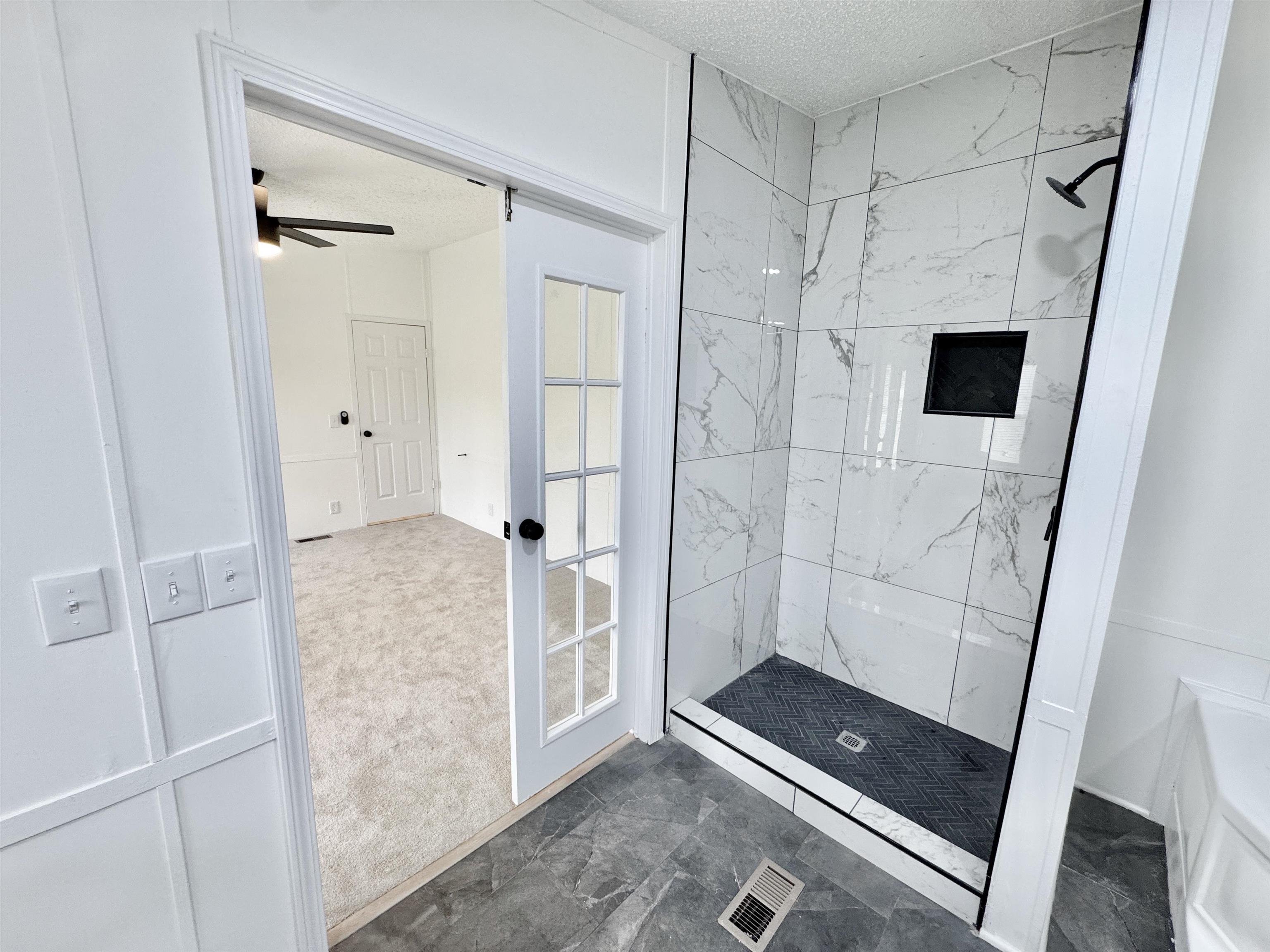 841 Simmons Road Drummonds, TN 38023 - Photo 19 of 35 Full bathroom featuring a textured ceiling, tiled shower, marble finish flooring, and ceiling fan