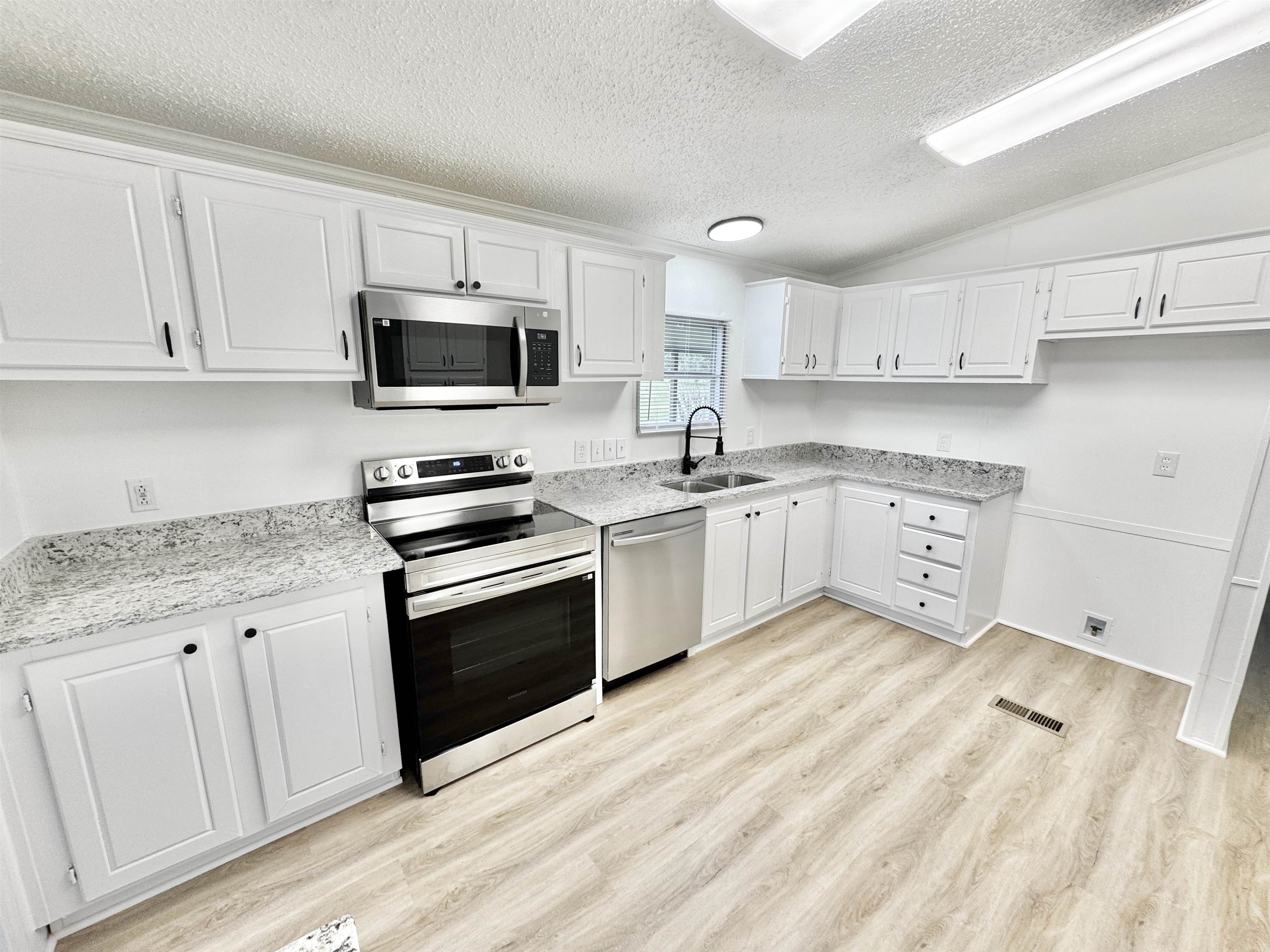 841 Simmons Road Drummonds, TN 38023 - Photo 3 of 35 Kitchen with appliances with stainless steel finishes, a sink, light wood finished floors, a textured ceiling, and white cabinetry