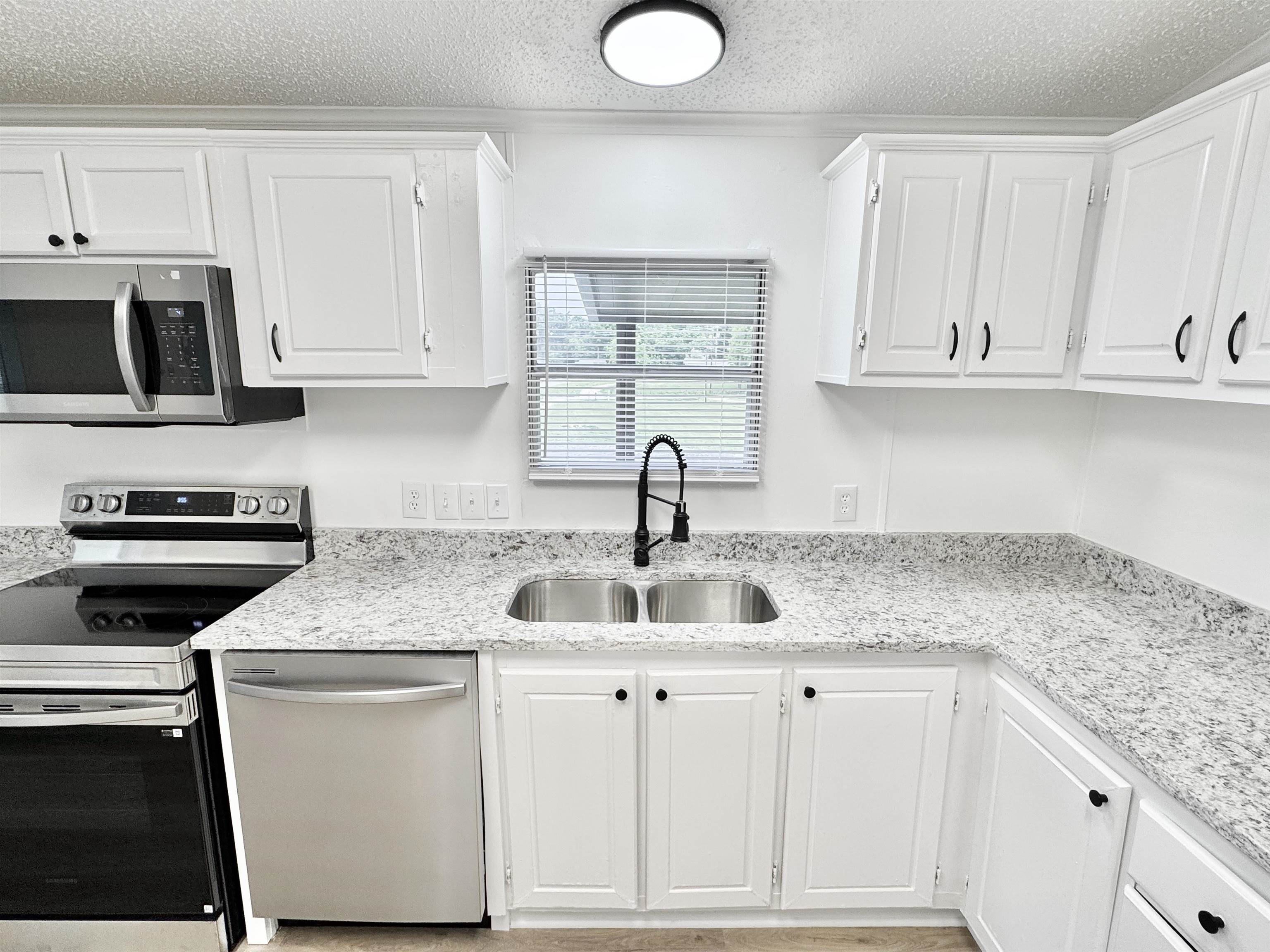 841 Simmons Road Drummonds, TN 38023 - Photo 4 of 35 Kitchen featuring stainless steel appliances, a sink, white cabinets, a textured ceiling, and light stone counters