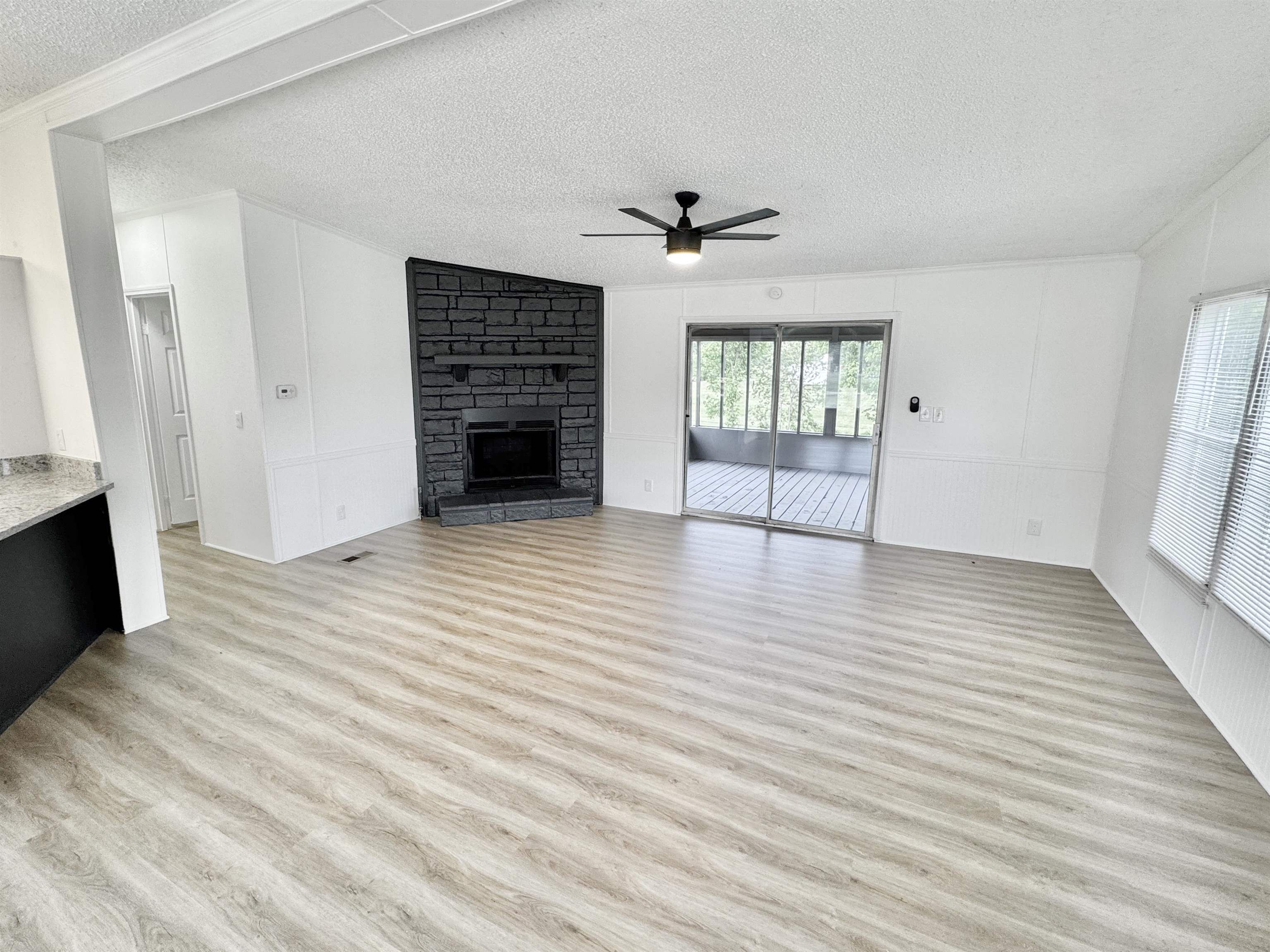 841 Simmons Road Drummonds, TN 38023 - Photo 6 of 35 Unfurnished living room featuring a textured ceiling, ceiling fan, light wood-type flooring, and a fireplace