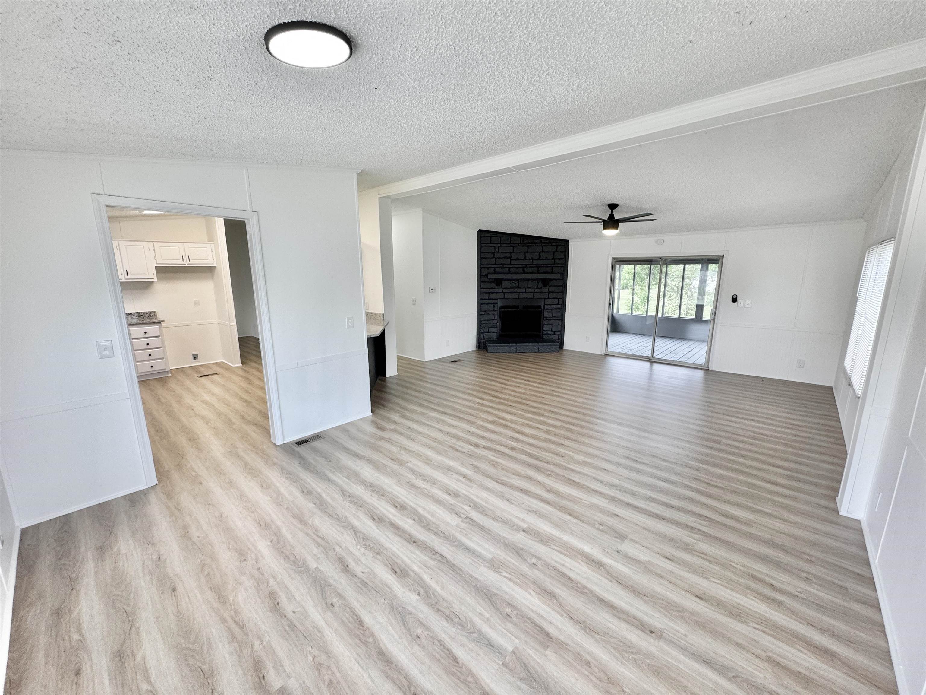 841 Simmons Road Drummonds, TN 38023 - Photo 9 of 35 Unfurnished living room featuring a textured ceiling, light wood-style flooring, a fireplace, and a ceiling fan