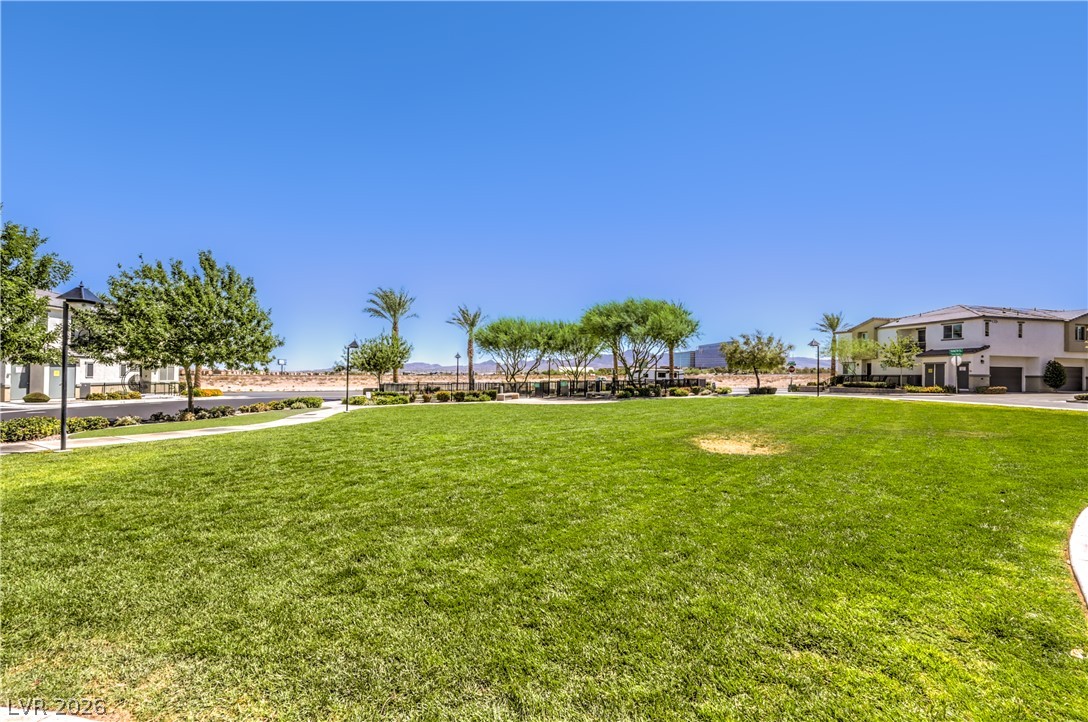 12103 Mojave Gold Road, Unit 4 Las Vegas, NV 89183 - Photo 22 of 23 A spacious community lawn lies bordered by manicured pathways, streetlights, and distant residential structures.
