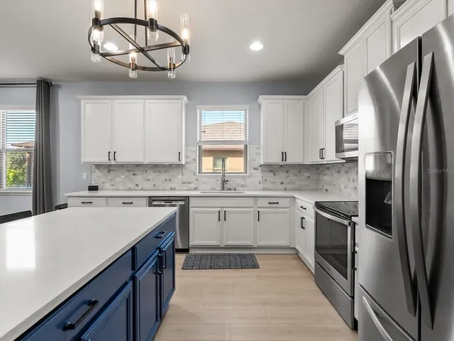 a kitchen with stainless steel appliances granite countertop a sink stove refrigerator and cabinets