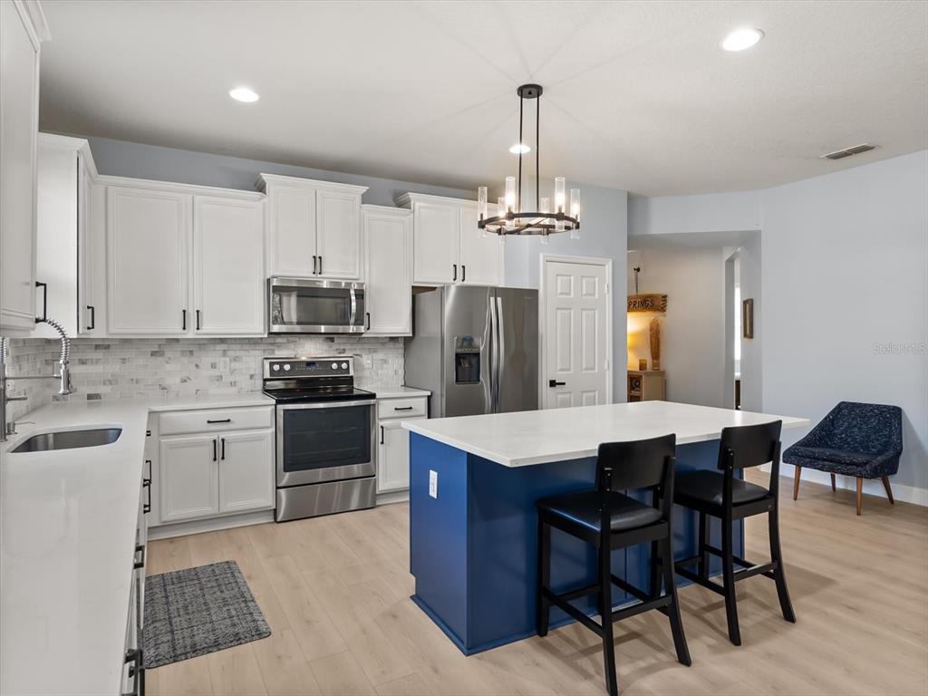 30021 Donnington Loop Mount Dora, FL 32757 - Photo 9 of 40 a kitchen with stainless steel appliances a sink a stove a table and chairs