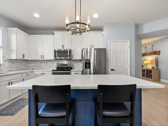 a kitchen with a dining table cabinets appliances and a counter top space