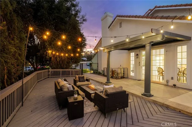 a view of a patio with couches table and chairs with wooden floor and fence