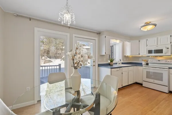 a kitchen with stainless steel appliances granite countertop a stove a sink dishwasher a dining table and chairs with wooden floor