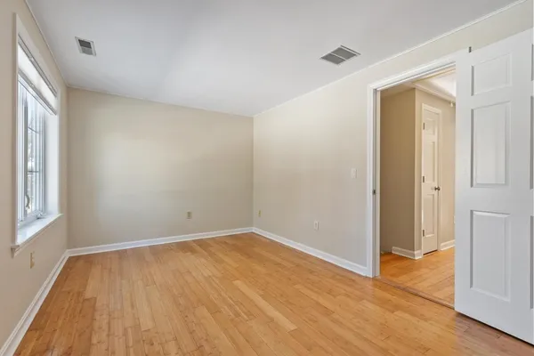 a view of an empty room with wooden floor and a window