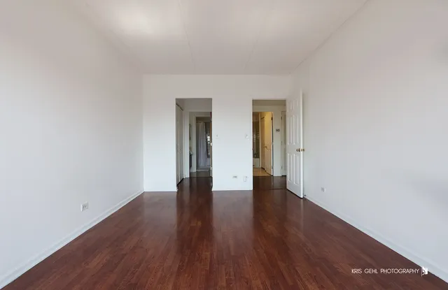 an empty room with wooden floor and natural light