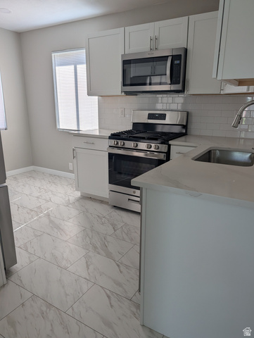 2880 Merton Way Magna, UT 84044 - Photo 30 of 30 Kitchen featuring white shaker-style cabinetry, stainless steel appliances, a subway tile backsplash, light-toned countertops, and large format floor tiling