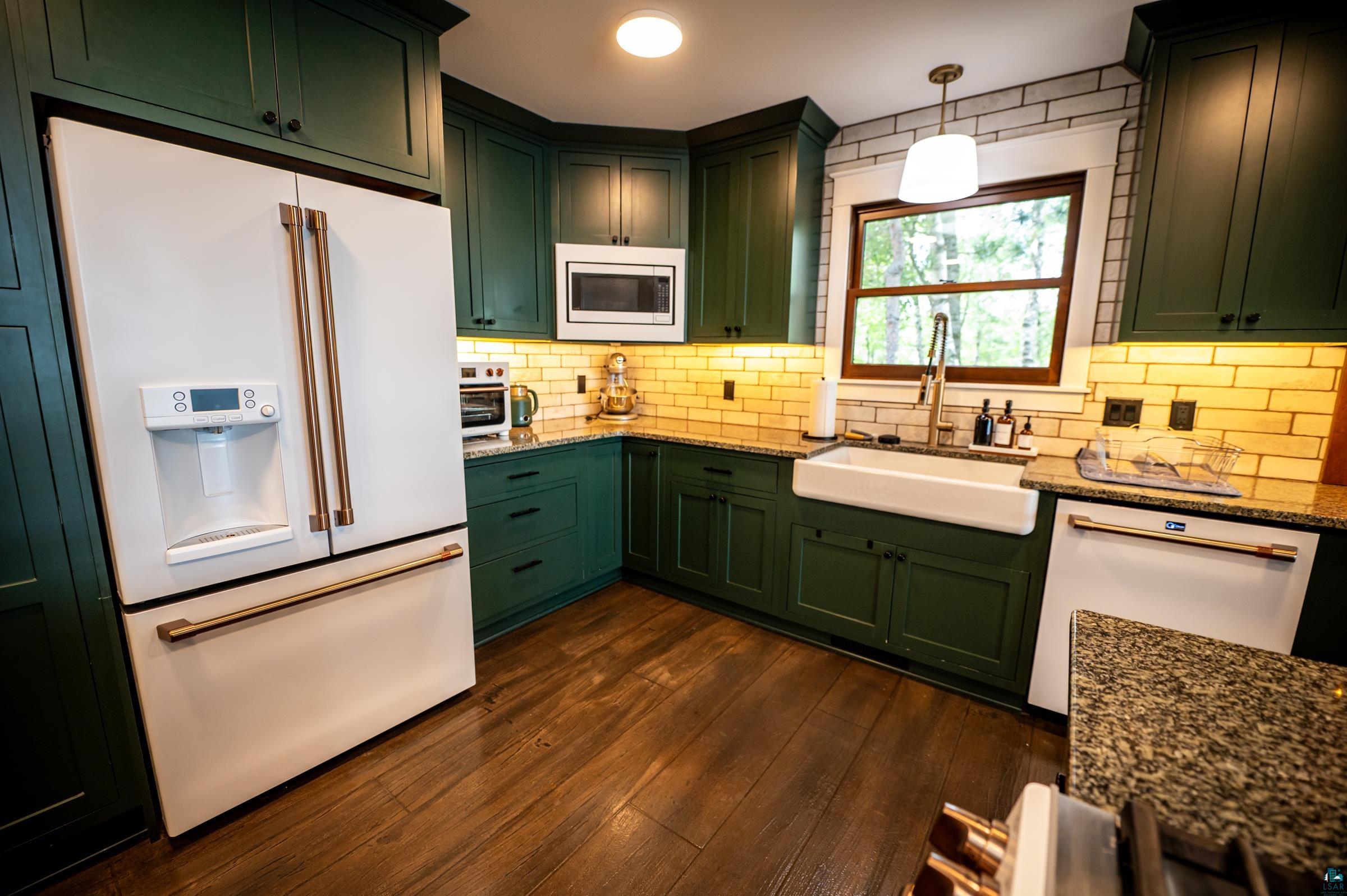 14635 Canadian Border Road Ely, MN 55731 - Photo 25 of 94 Kitchen featuring dark green cabinetry, a white farmhouse sink, wood-finish flooring, a white French door refrigerator, and speckled countertops