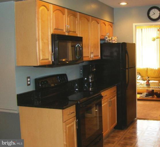 11603 Windbluff Court Reston, VA 20191 - Photo 3 of 22 a kitchen with granite countertop a refrigerator a stove and a microwave