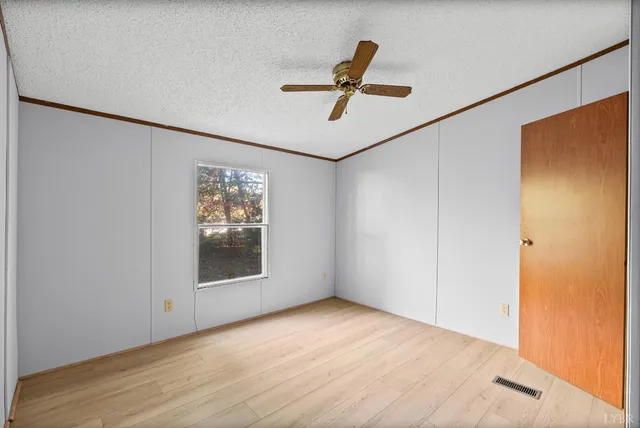 a view of a big room with wooden floor a ceiling fan and windows
