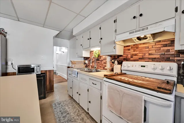 a kitchen with stainless steel appliances a stove a sink and white cabinets