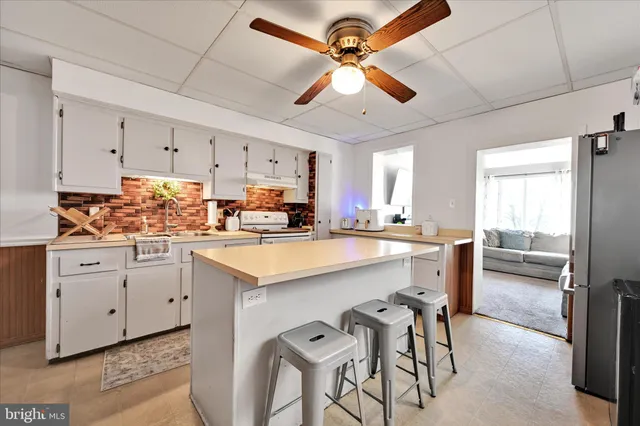 a kitchen with stainless steel appliances kitchen island granite countertop a table chairs sink and cabinets