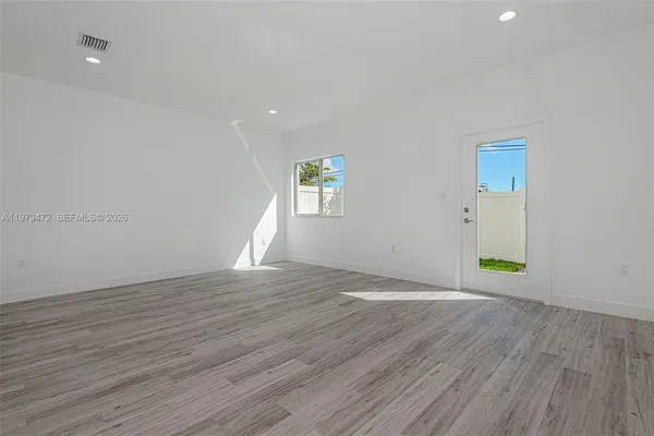 an empty room with wooden floor and windows