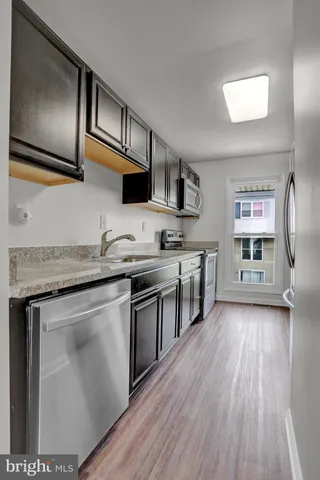 a kitchen with stainless steel appliances granite countertop a stove a refrigerator and wooden floor