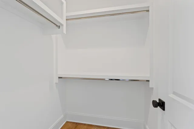 a view of an empty room with wooden floor and closet