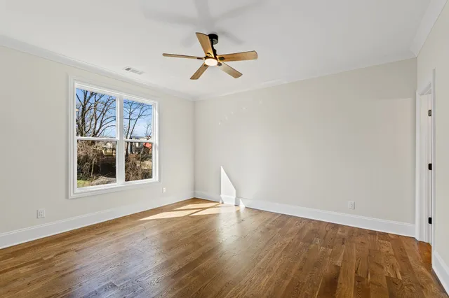 a view of empty room with wooden floor and fireplace