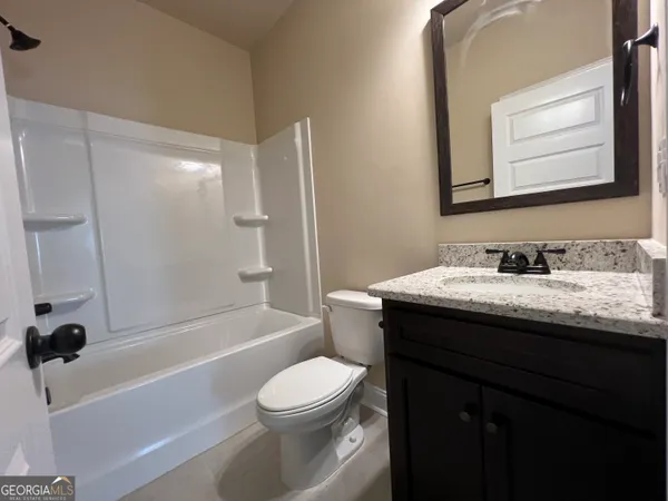 a bathroom with a granite countertop sink toilet a mirror and shower