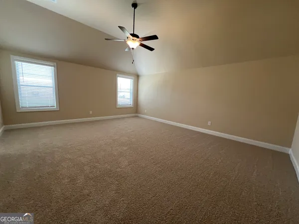 an empty room with a chandelier fan and windows