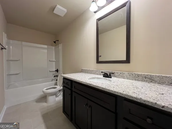 a bathroom with a granite countertop sink mirror vanity and toilet