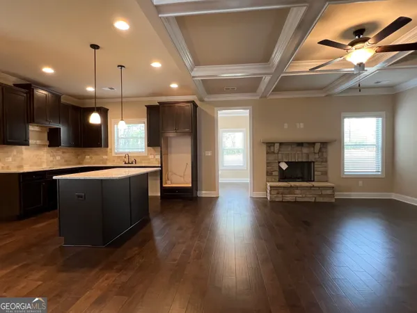 a large kitchen with stainless steel appliances kitchen island a large counter tops a stove a sink dishwasher and a fireplace with wooden floor