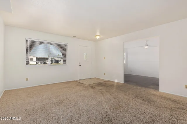 an empty room with a large window and a ceiling fan
