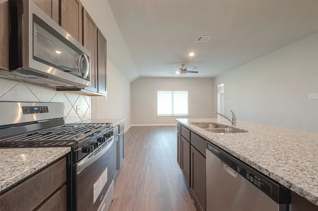 a kitchen with granite countertop stainless steel appliances a sink stove and cabinets