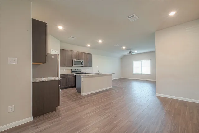 a view of kitchen with kitchen island wooden floors and stainless steel appliances