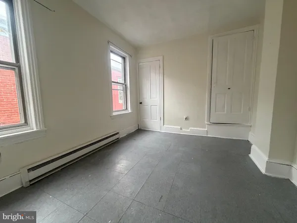 an empty room with windows and cabinet