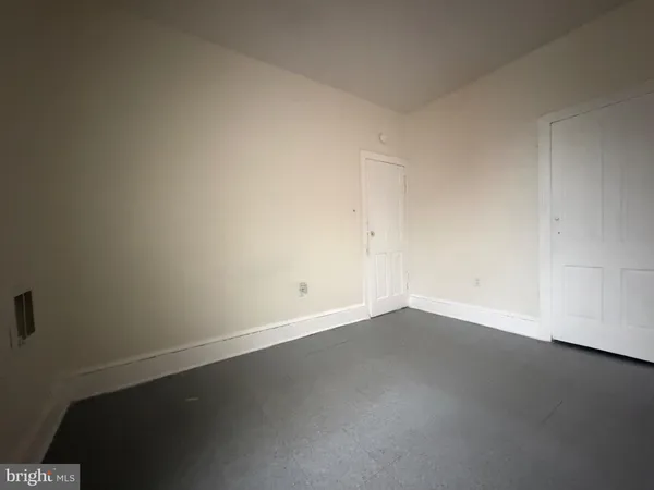 a view of a hallway with wooden floor and a bathroom