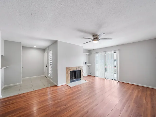 an empty room with wooden floor fireplace and windows