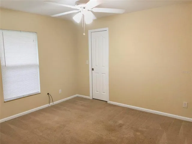 an empty room with a window and a fan
