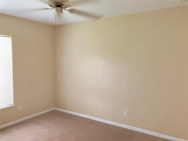 an empty room with a window and a fan