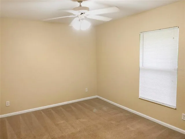 an empty room with a window and a fan