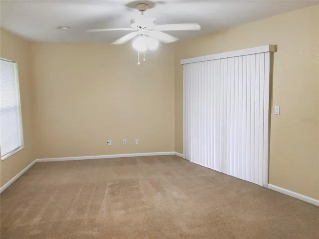 an empty room with a chandelier fan and windows