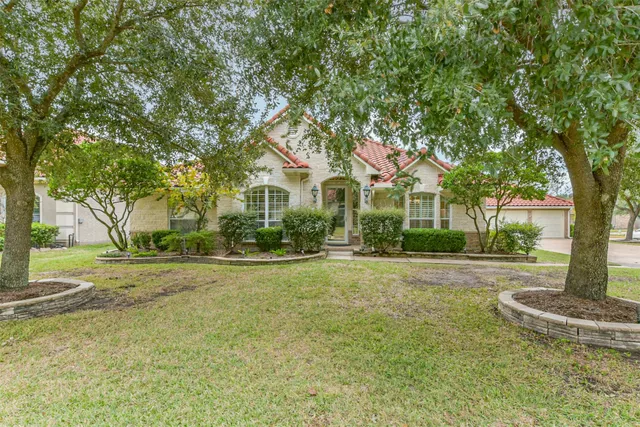 a front view of a house with a garden and tree