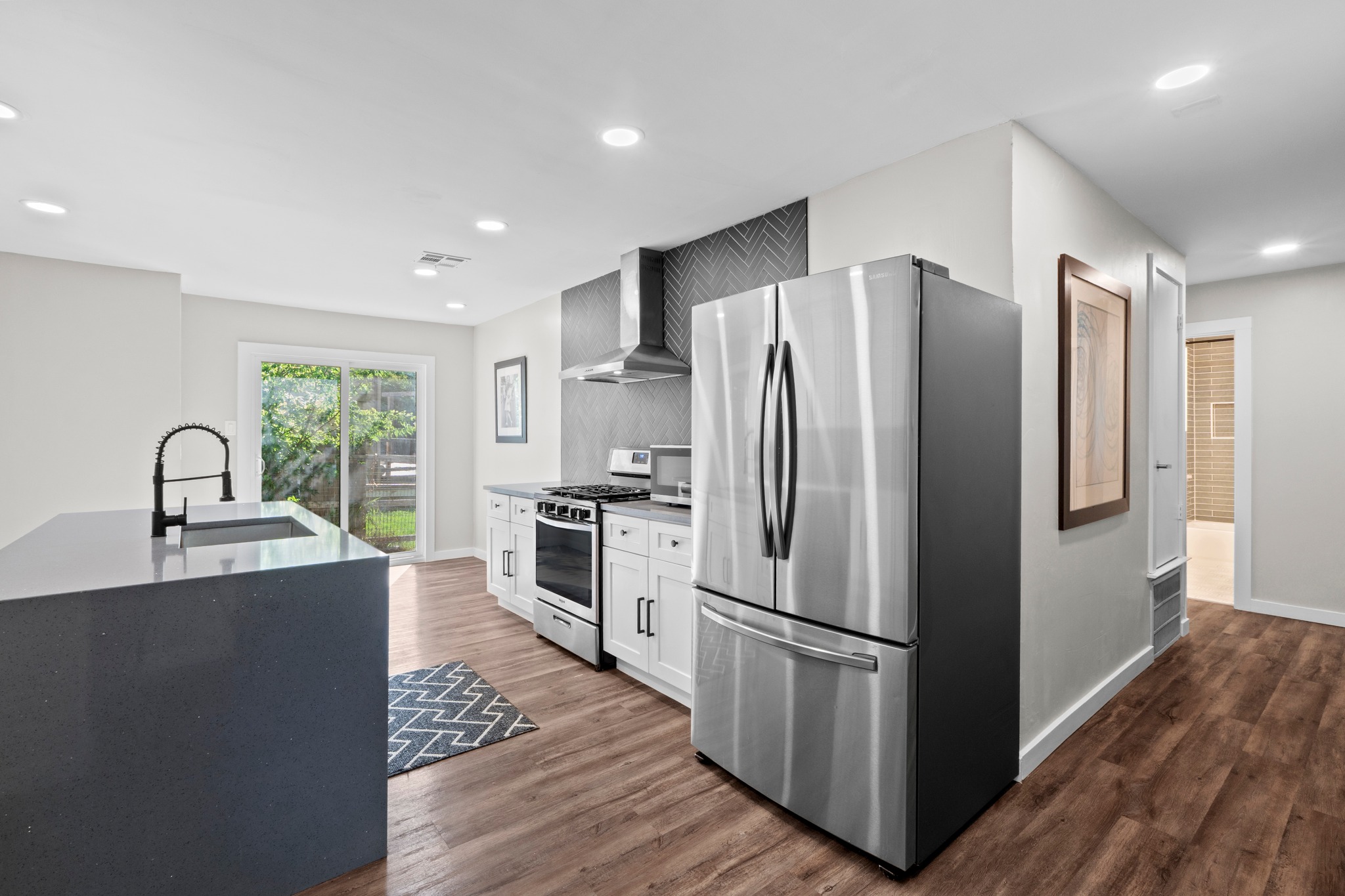 11811 Rotherham Drive Austin, TX 78754 - Photo 7 of 37 A contemporary kitchen features sleek stainless steel appliances and rich wood flooring, ideal for culinary adventures.