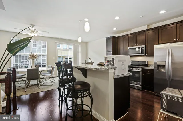 a kitchen with stainless steel appliances a table chairs refrigerator and chairs