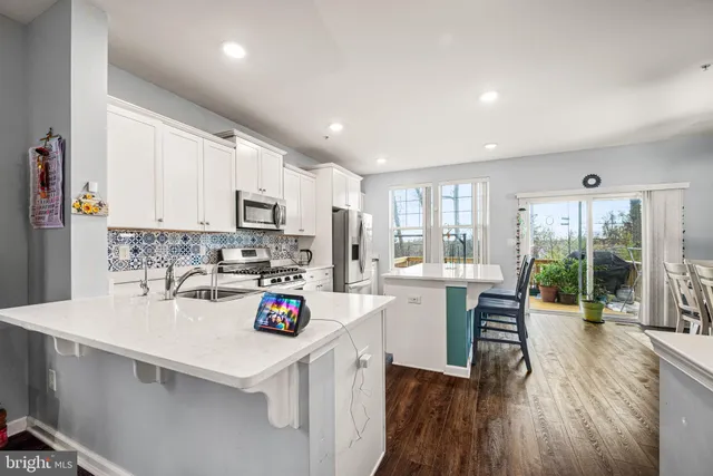 a kitchen with a sink dishwasher stove and white cabinets with wooden floor