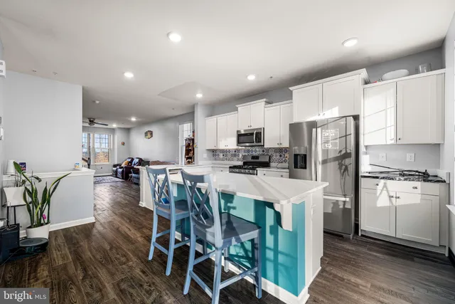 a kitchen with stainless steel appliances a refrigerator a stove a sink dishwasher a oven with white cabinets and wooden floor