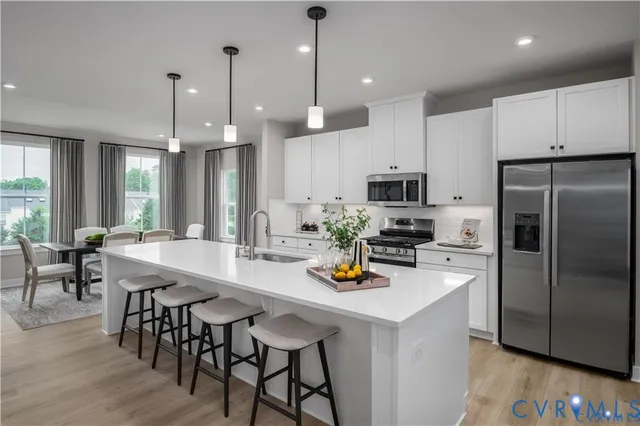 a kitchen with stainless steel appliances a dining table chairs refrigerator and stove top oven