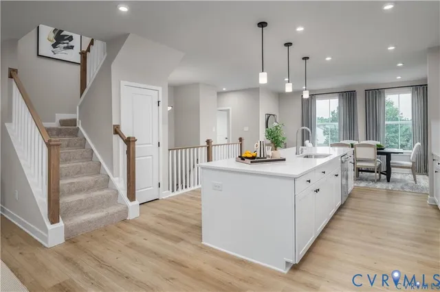a large white kitchen with a large counter top a sink a window and stainless steel appliances