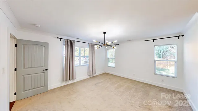 an empty room with a chandelier fan and windows