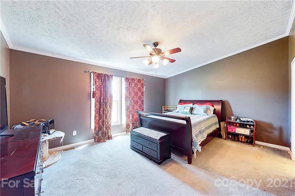 4407 Wolf Pond Road Monroe, NC 28112 - Photo 17 of 26 a bedroom with a bed and a chandelier