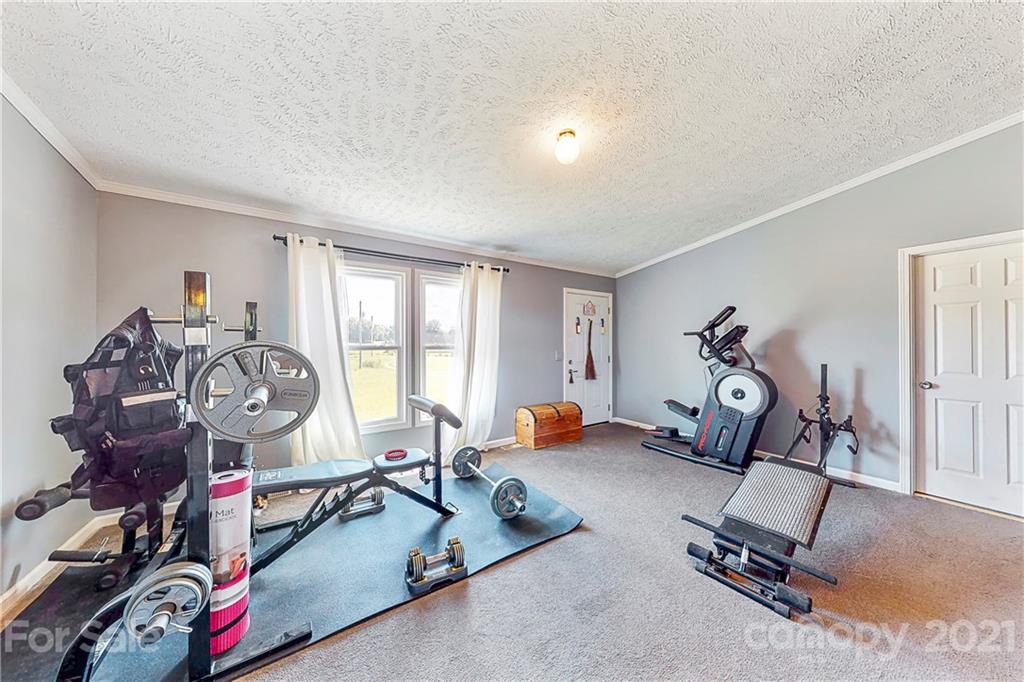 4407 Wolf Pond Road Monroe, NC 28112 - Photo 8 of 26 a room with gym equipment and a large window