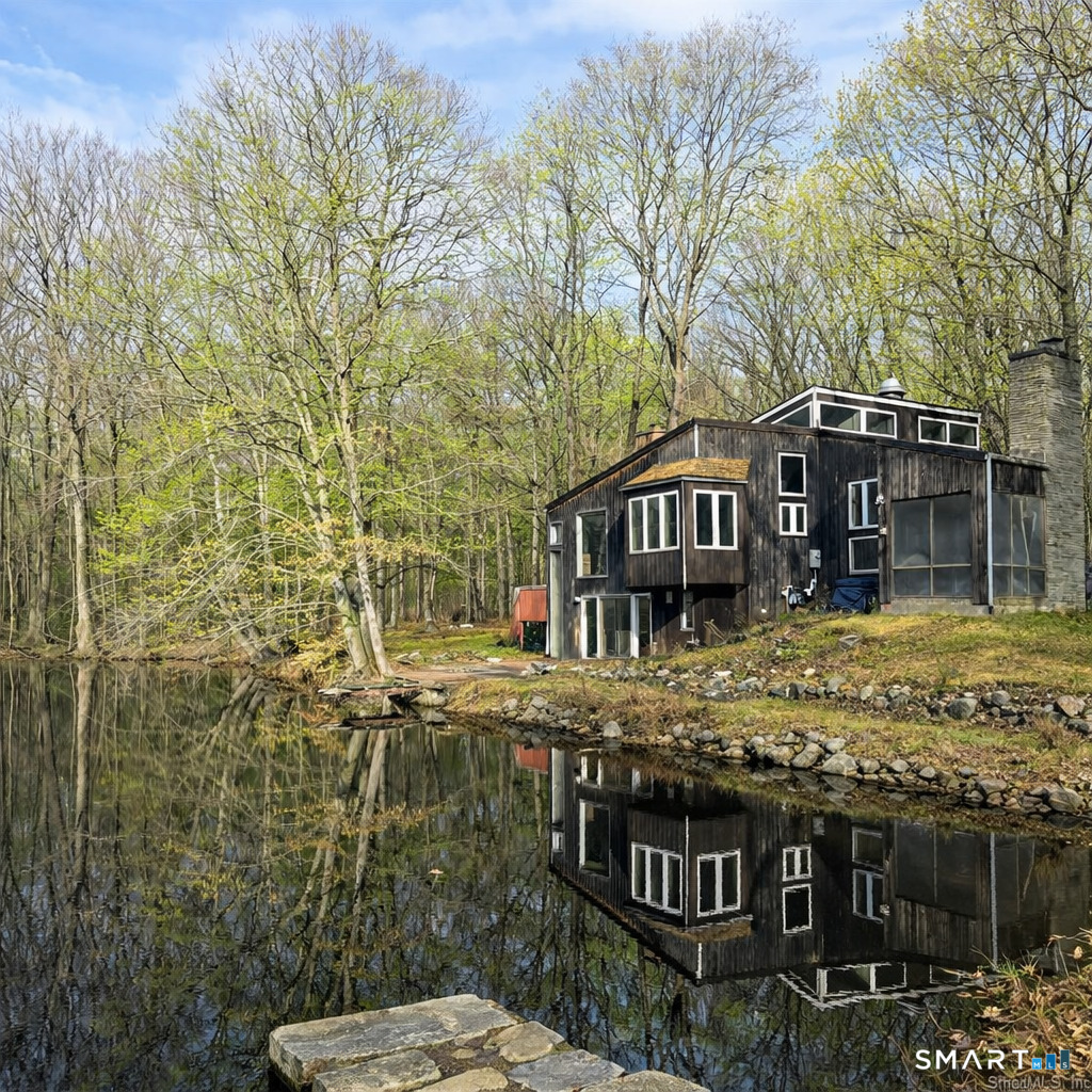a view of a house with a small yard and large trees