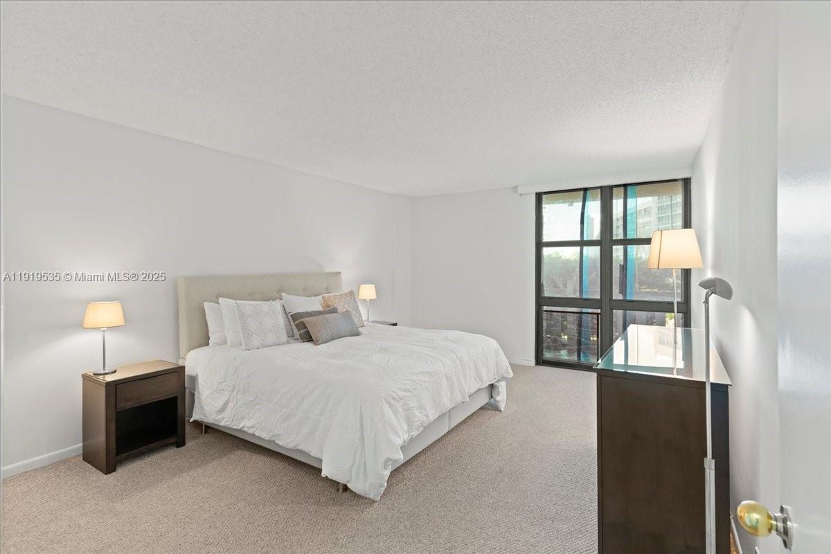 1121 Crandon Boulevard, Unit E304 Key Biscayne, FL 33149 - Photo 8 of 17 a bedroom with a bed and a lamp