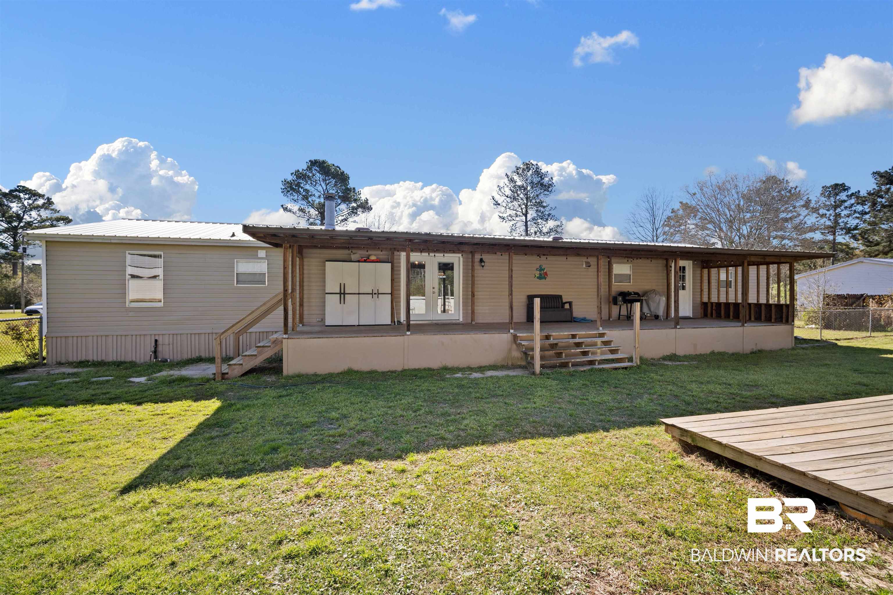 9011 Wilmer Georgetown Road Wilmer, AL 36587 - Photo 28 of 34 Rear view of property featuring a lawn, fence, a wooden deck, and french doors